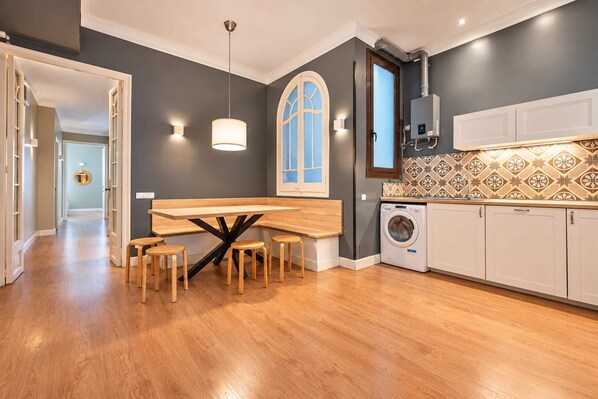 A modern kitchen with a central island, built-in appliances, and a patterned backsplash.