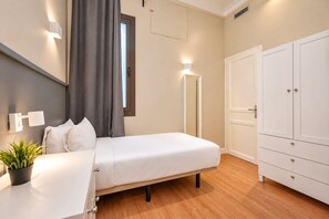 A bedroom with a bed, a wardrobe, a bedside table with a plant, and a window with curtains. - Sweett | Sepulveda 2A (Barcelona)