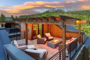 A rooftop patio with outdoor furniture, a fire pit, and a pergola.