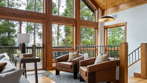 A spacious living room with large windows, wooden flooring, and a staircase. - Silver Lining Chateau 374 I Amazing Views I Private Hot Tub I Bunk Room I Discounted Attractions (Tabernash)