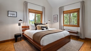 A bedroom with a wooden bed, two windows with curtains, a bedside table, and a lamp. - Silver Lining Chateau 374 I Amazing Views I Private Hot Tub I Bunk Room I Discounted Attractions (Tabernash)