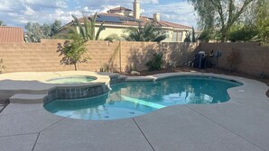 Una piscina con hidromasaje, rodeada por un muro de ladrillo y palmeras.