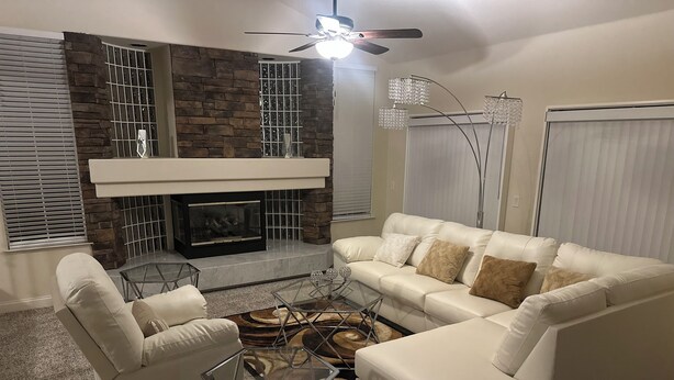 Una sala de estar con chimenea, sofá de cuero blanco y una mesa de centro de vidrio.