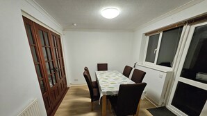 Une salle à manger avec une table, des chaises, un radiateur, une porte et une fenêtre.