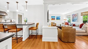 A spacious living area with a sofa, a coffee table, and a dining area with chairs and a kitchen counter. - 5BDRM Renovated Historic | Downtown| Shuttle| Bike Path (Stowe)