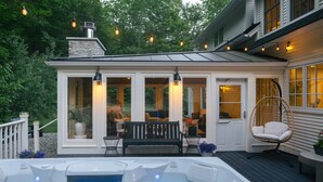 A covered outdoor area with a hot tub, seating, and string lights.