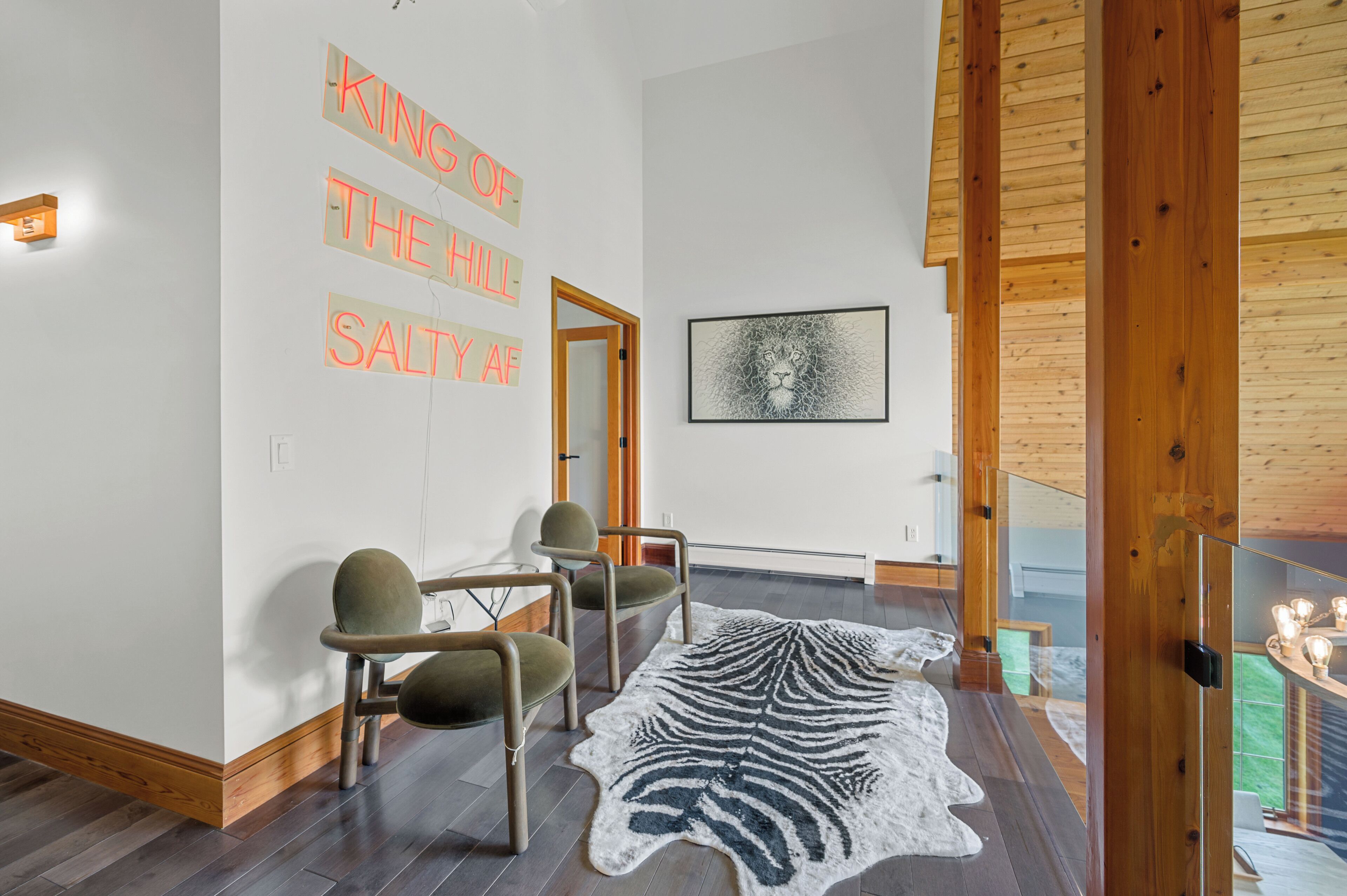 A modern interior with a zebra print rug, wooden flooring, and a wall with illuminated text.