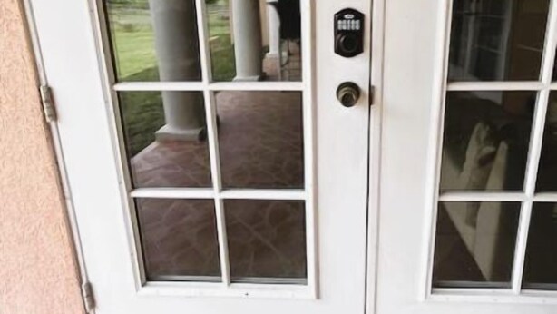 A white door with a keypad lock, a glass panel, and a stone-tiled entrance. - Quiet Lakeview Home (Wesley Chapel)