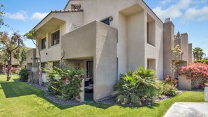 A two-story house with a stucco exterior, a front porch, and a well-maintained garden with various plants and flowers.