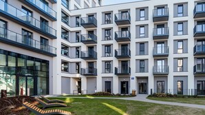 Un edificio residencial moderno de varios pisos, con balcones, un patio central y un sendero.