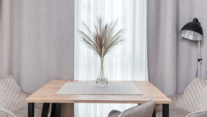 Un comedor moderno con una mesa de madera, un florero con plantas secas y una lámpara de pie negra.