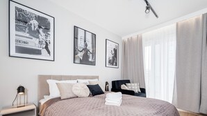 Un dormitorio moderno con una cama grande, una mesita de noche, una silla y tres cuadros en la pared.
