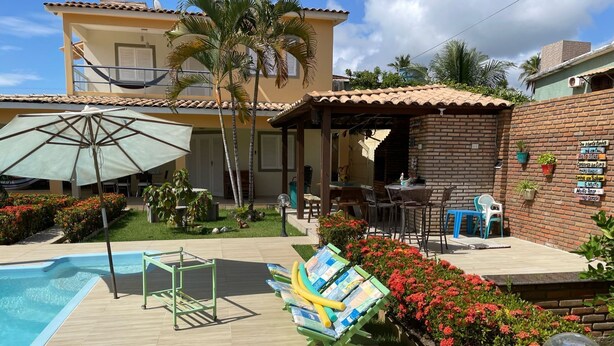 Un espace aménagé au bord de la piscine, comprenant une piscine, des chaises longues et une terrasse avec des sièges d’extérieur.