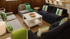 En moderne stue med sofa, lænestole, et sofabord og et spiseområde med stole.
