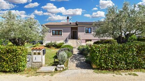 Een twee verdiepingen tellend huis met een voordeur, een kleine tuin en een pad naar de deur.