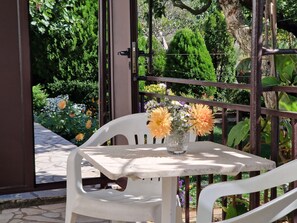 A white plastic chair and table with a vase of flowers in a garden setting.