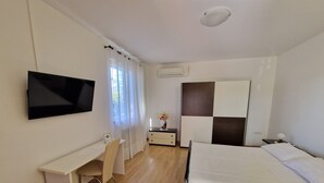 Ein modernes Hotelzimmer mit einem Bett, einem Schreibtisch, einem Sessel, einem Fernseher und einem Kleiderschrank.