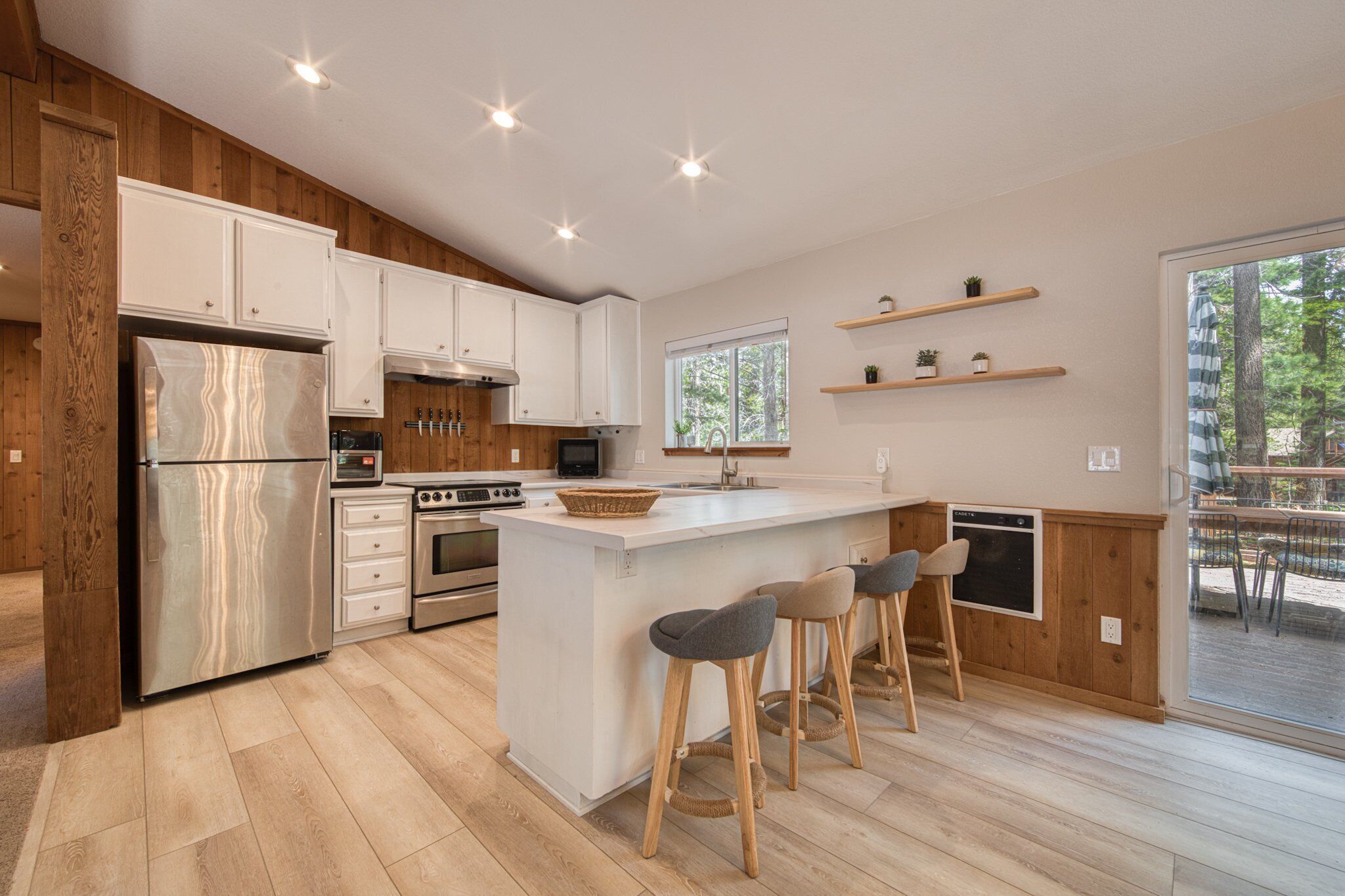 Una cocina moderna con armarios de madera, un refrigerador de acero inoxidable, horno empotrado y una isla grande con taburetes de bar.