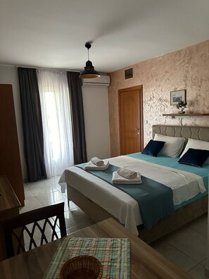 A bedroom with a bed, a wooden door, a ceiling fan, and a window with curtains.