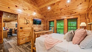 A wooden cabin with a bed, a TV, and a dining area.