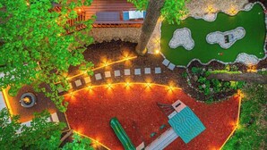 Ein runder Außenbereich mit Rutsche, kleinem Pool und Holzterrasse.