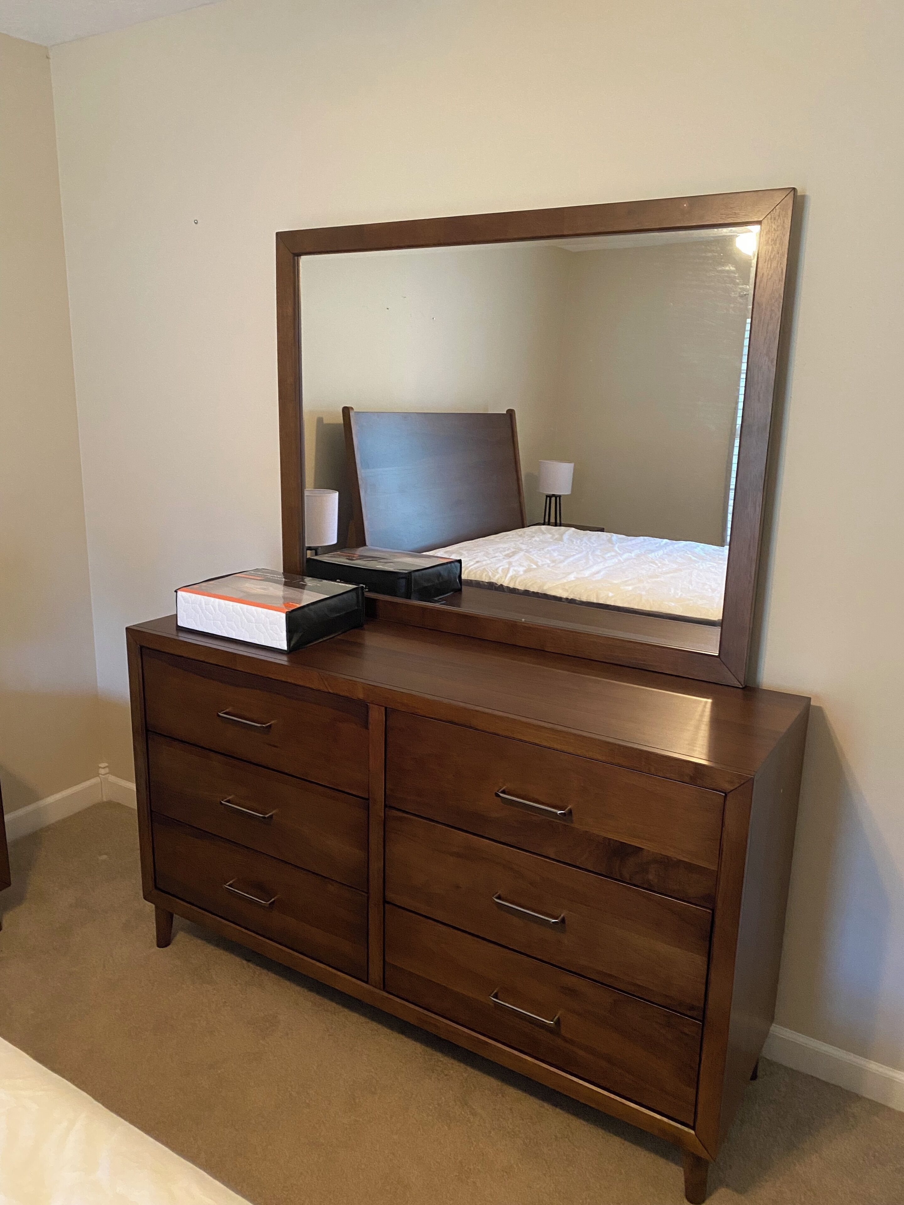 Een houten dressoir met lades en een spiegel erboven.