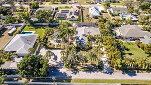 Vue aérienne d’un quartier résidentiel avec des maisons, des panneaux solaires et des palmiers.