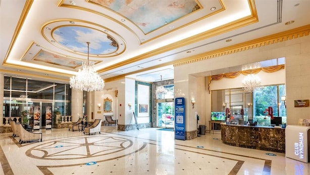 A spacious lobby with a marble floor, a reception desk, and a chandelier.