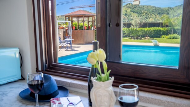 A kitchen counter with a view of a swimming pool, a gazebo, and a mountain landscape. - Villa Agave - Room & Pool (Gaggi)