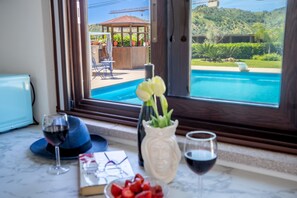A kitchen counter with a view of a swimming pool, a gazebo, and a mountain landscape. - Villa Agave - Room & Pool (Gaggi)
