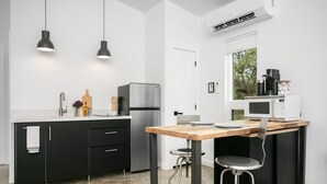 Een moderne keuken met een zwart aanrecht, roestvrijstalen apparatuur en hanglampen.