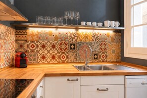 A kitchen with a patterned backsplash, a stainless steel sink, and a coffee machine. - Sweett | Sepulveda Principal C (Barcelona)