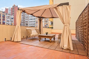 A terrace with a table, two chairs, and a canopy.