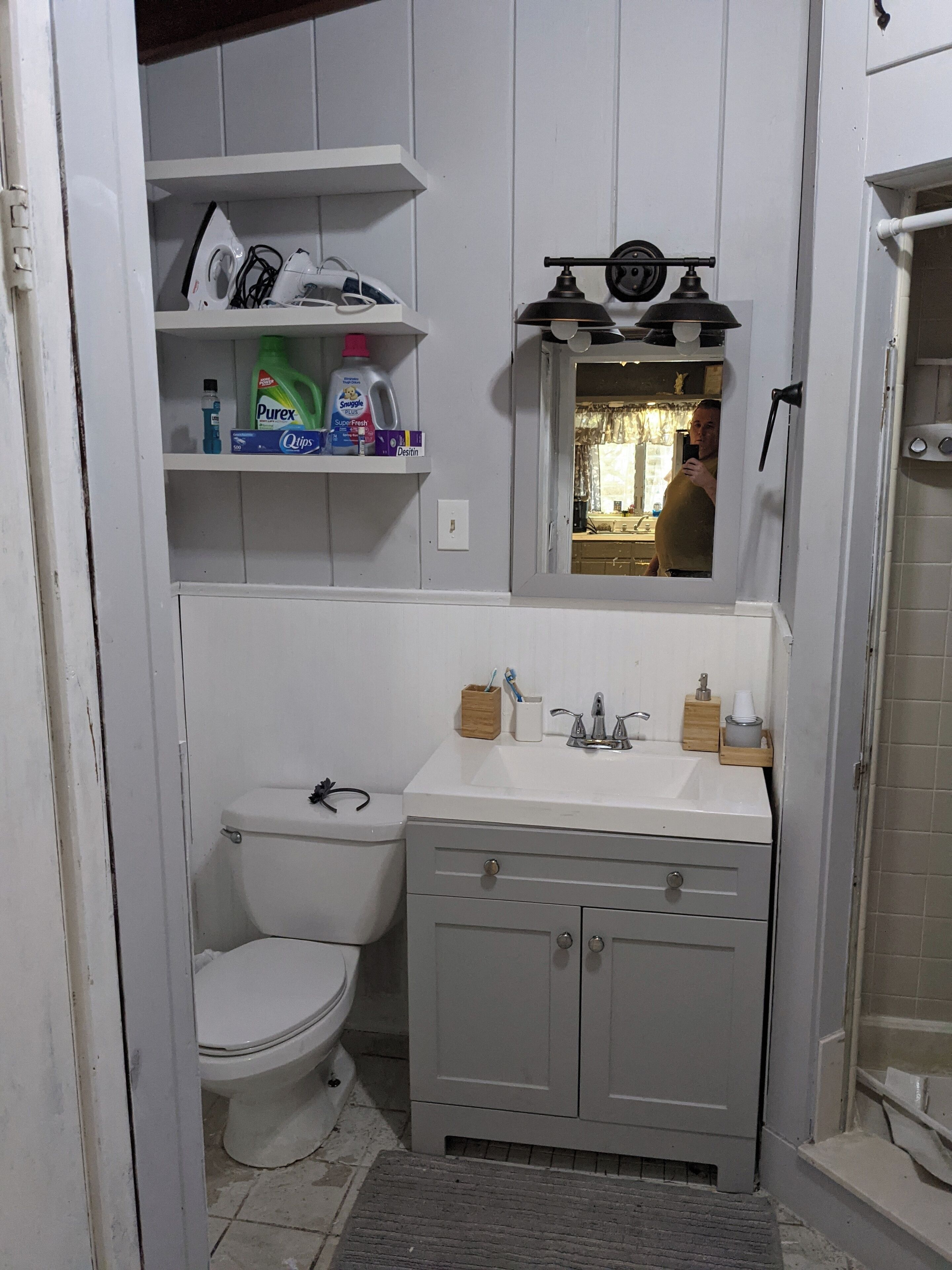 A compact bathroom with a toilet, a sink with a mirror above it, and a shower area.