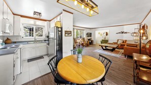 A modern kitchen with white cabinets, a wooden dining table, and a built-in oven. - Charming 3-bedroom cabin with AC, WiFi in serene Idyllwild-Pine Cove (Idyllwild-Pine Cove)