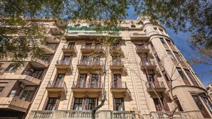 A multi-story building with balconies, a green awning, and a clear sky. - Sweett | Sepulveda 3C (Barcelona)