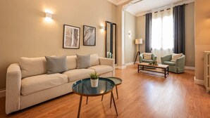 A living room with a sofa, two armchairs, a coffee table, and a mirror. - Sweett | Sepulveda 3C (Barcelona)