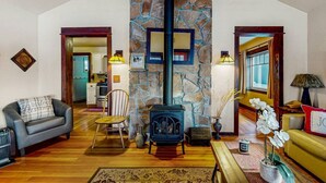 A spacious living room with a stone fireplace, wooden flooring, and a cozy seating area.