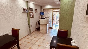 A dining area with hexagonal patterned tiles, a reception desk, and a television. - Sera Hotel (Istanbul)