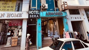 A hotel with a blue entrance, a visible sign for 'Hotel Sera', and a 'BNZ' logo on a car in front. - Sera Hotel (Istanbul)