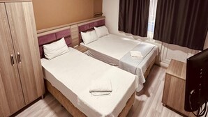 A hotel room with two beds, a wardrobe, a desk, and a television. - Sera Hotel (Istanbul)