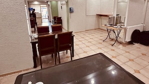 A room with a dining table, chairs, a small kitchen area, and a white textured wall. - Sera Hotel (Istanbul)