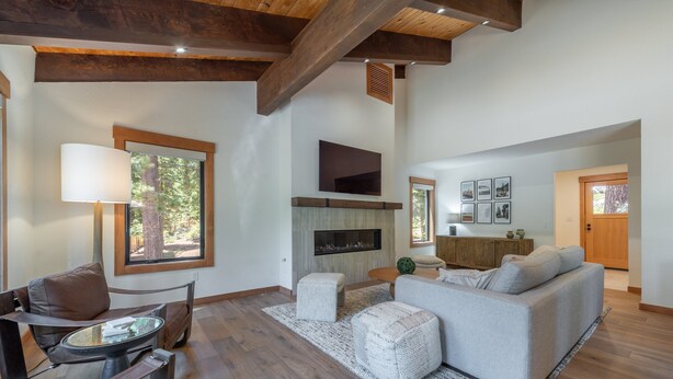 A spacious living room with a fireplace, a sofa, a coffee table, and a TV mounted on the wall. - Carnelian Crest, modern 3BR cabin with hot tub - perfect Couples Retreat! (Carnelian Bay)
