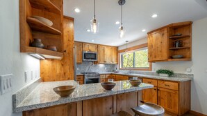 A kitchen with wooden cabinets, granite countertops, and bar stools. - Carnelian Crest, modern 3BR cabin with hot tub - perfect Couples Retreat! (Carnelian Bay)