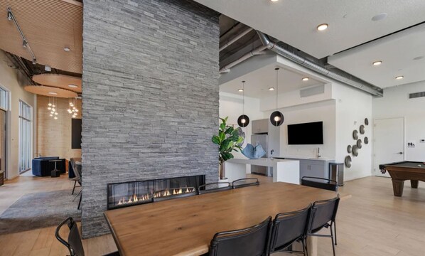 Une cuisine moderne dotée d’un îlot central, un coin repas avec une table en bois et un espace de vie agrémenté d’une cheminée.