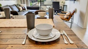 Une table à manger dressée avec un saladier, des assiettes et des couverts.