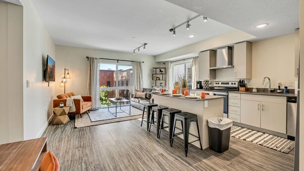 A modern kitchen with a central island, bar stools, and a dining area with a wooden table and chairs. - Desert at Paperbox in Salt Lake City (Salt Lake City)