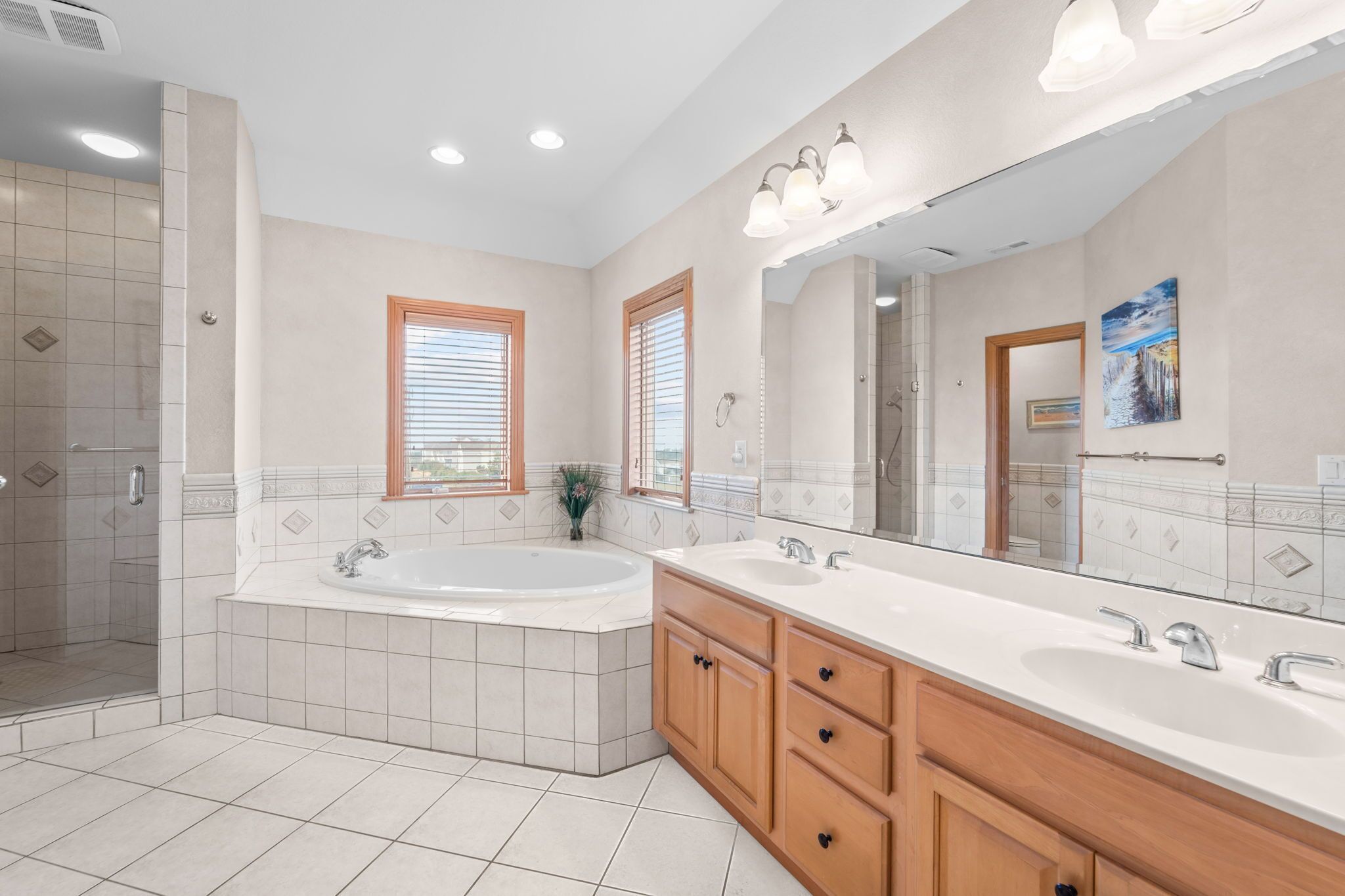A modern bathroom with a large bathtub, double sinks, and a walk-in shower.