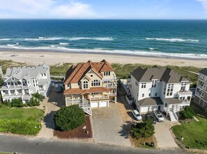 Ein Strandgrundstück mit mehreren Gebäuden, darunter ein großes Haus mit Balkon und ein kleinerer Anbau.