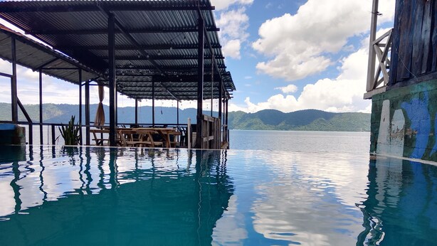 Una piscina infinita con vistas a montañas y un cielo despejado.